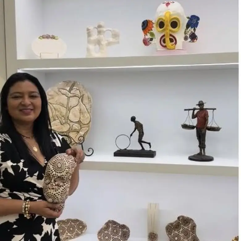Mariale Pineda, founder of Bohemia Handmade Studio, beside a gallery wall of her fiber and sculpture work