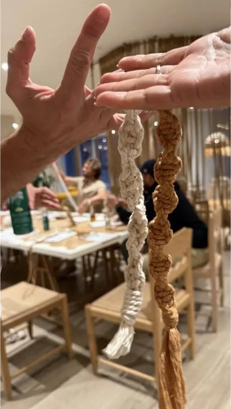 Hands tying macram&eacute; knots at a long workshop table during a beginner class in Miami