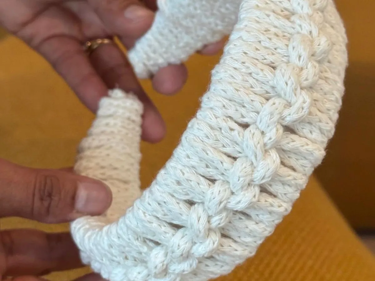 White macram&eacute; headband with a braided center held in two hands