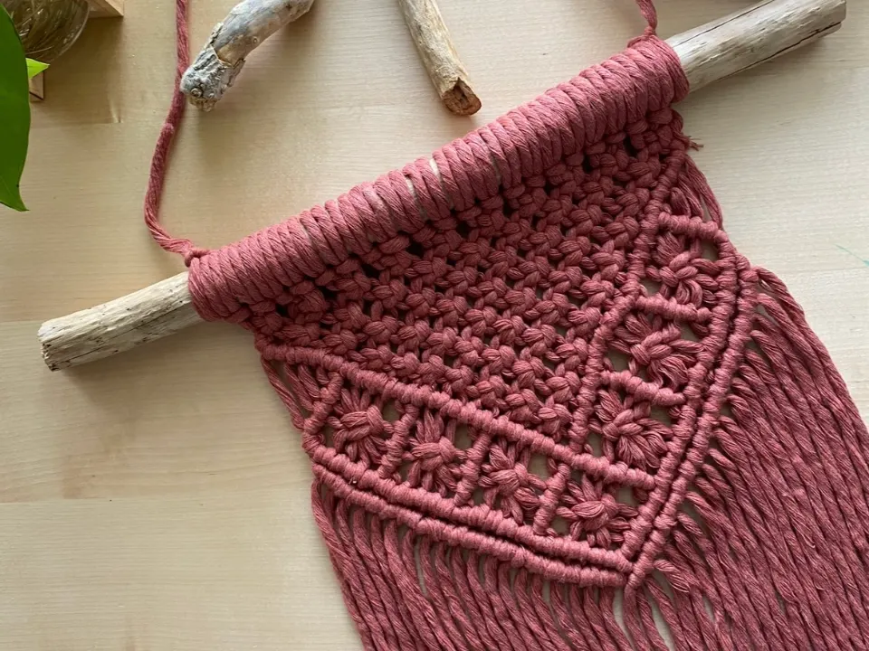 Tapiz de macramé rosa terracota con flecos, montado en driftwood