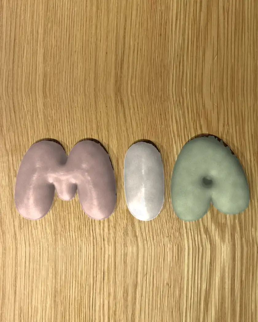 Custom 3D plaster name sign spelling MIA, hand-cast letters hand-painted in matte dusty rose, cream and sage on an oak table